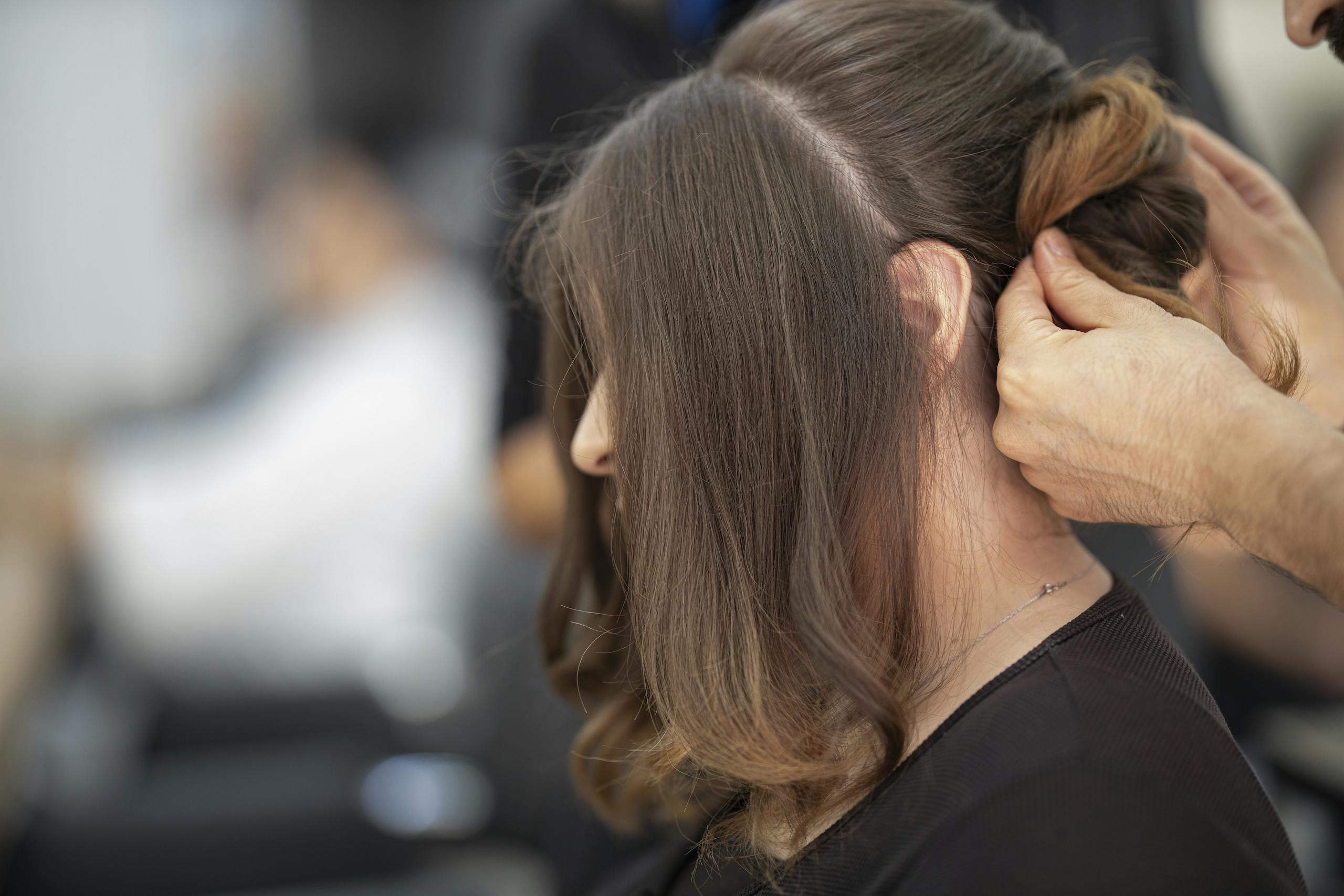 Close-up of a hairstylist creating an elegant hairstyle for a woman in a salon.